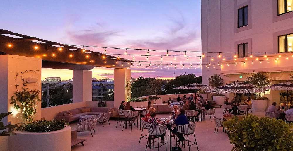 Mamey Rooftop Restaurant: A rooftop restaurant in Miami with string lights illuminating the outdoor patio at dusk.