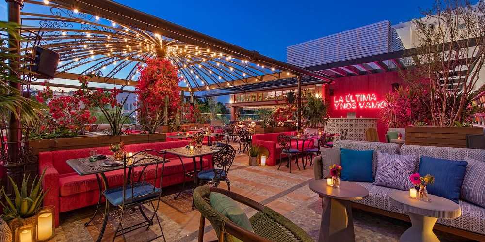 Serana Rooftop Restaurant in Miami: A rooftop patio featuring red couches and red lights, perfect for dining with breathtaking views in Miami.