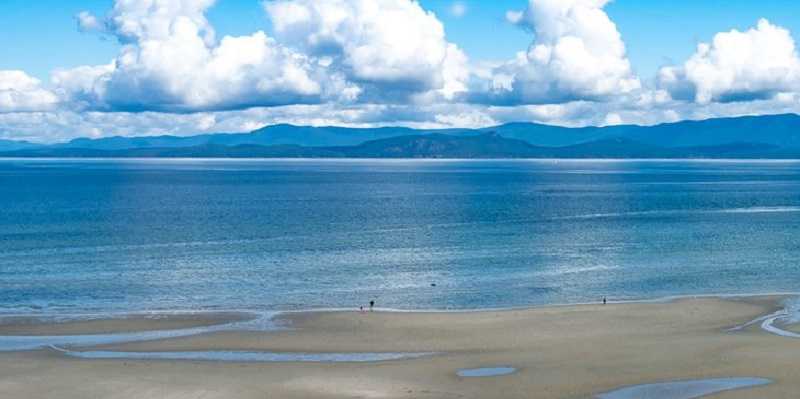A sandy beach with mountains in the background, located in Parksville.