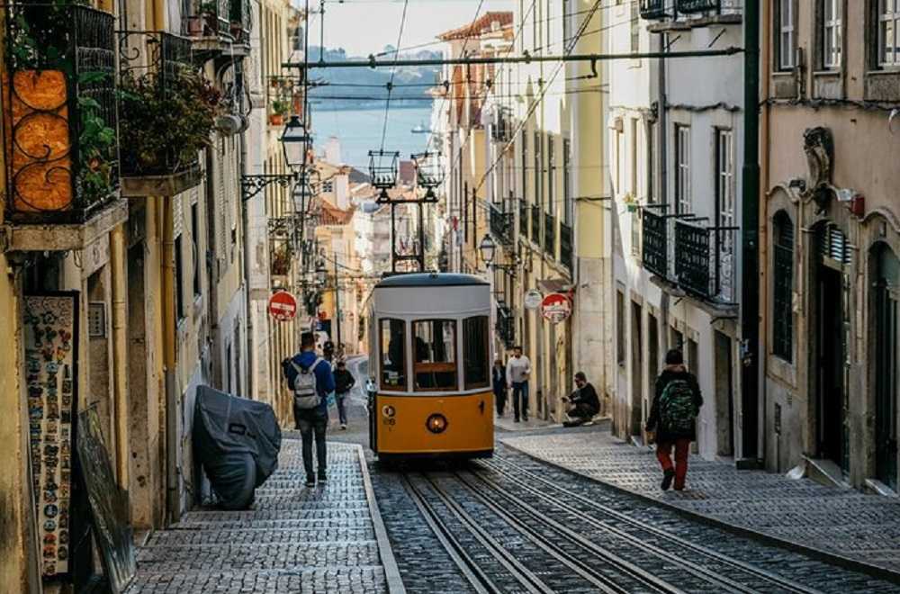 Best things to do in Lisbon: A yellow tram is going down a narrow Bairro Alto street.