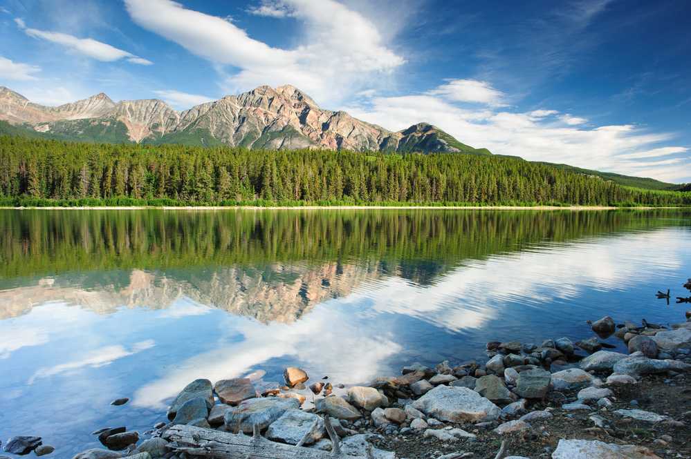 Explore Edmonton: In Edmonton, a mountain range is beautifully reflected in a scenic lake.