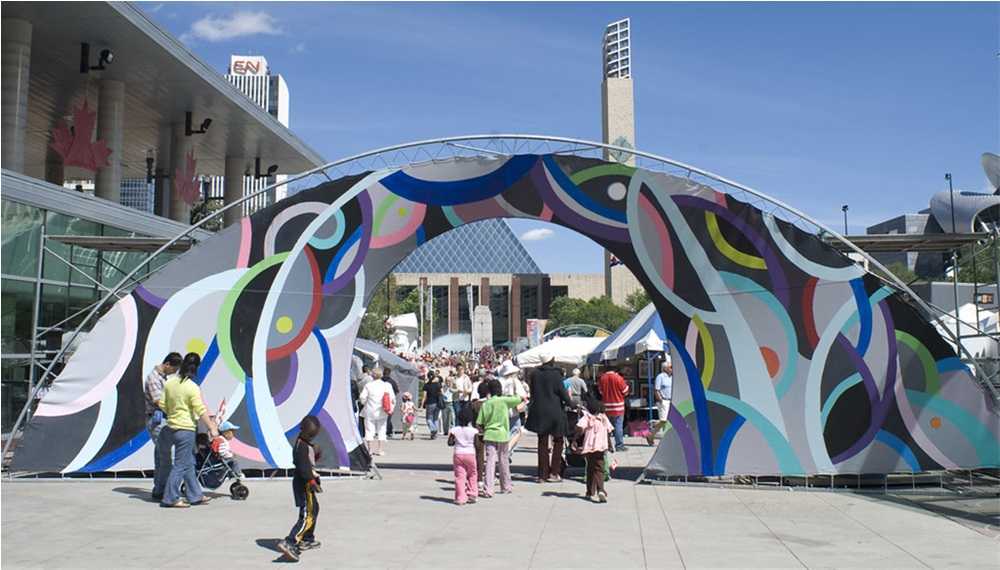 A group of people walking in front of a colorful arch at festivals in Edmonton.