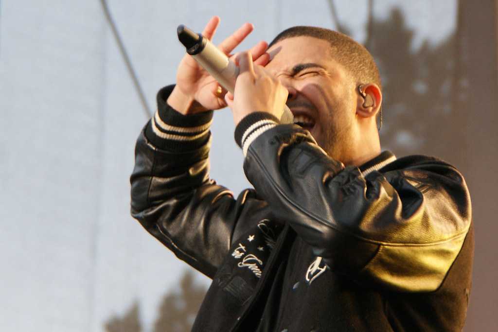 A man in a black jacket singing into a microphone in the Canadian Rockies.