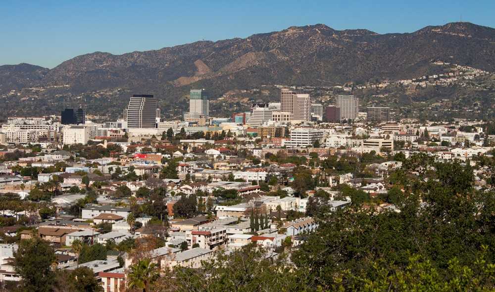 A city with trees and mountains in the background, renowned as one of the safest cities in America.