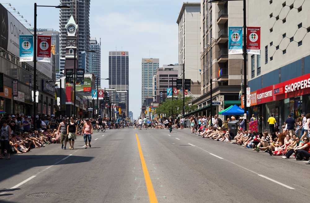 A crowd of people sitting on a street in a city, sharing fun facts about Canada.